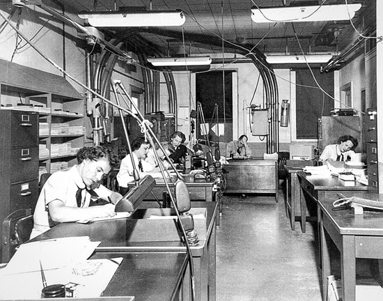 After a WAVE completed a run on her bombe (which took 20 minutes) she gave her print out to her supervisor for verification. The supervisor then took the results to the Watch Office for logging. The verified and logged results were sent via a pneumatic tube system to the cryptanalysts located in Building 2. (National Archives and Records Administration)
